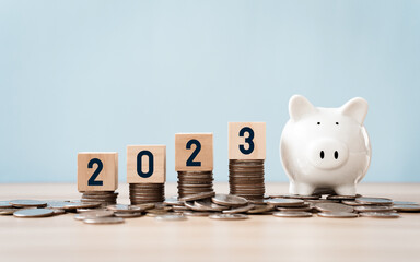 Wall Mural - wooden cube year 2023 on top stack of coins with sky blue background and copy space. saving money and financial plan concept for investment in new year 2023..