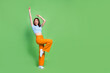 Full size photo of crazy carefree girl raise hands dancing look empty space isolated on green color background