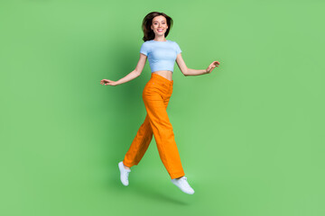 Wall Mural - Full body profile portrait of carefree pretty lady jump hurry rush isolated on green color background