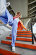 © Seventyfour - Portrait of young carefree woman wearing street style fashion outdoors in urban setting and kicking up to camera