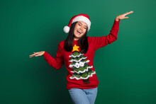 Photo Of Pretty Cute Relaxed Japanese Woman Raise Hands Up Active Motion Dancing Xmas Music Wear Ugly Sweater Isolated On Green Color Background