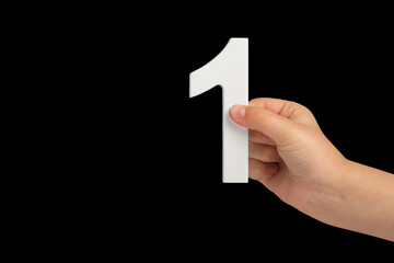 Aufkleber - Number one in a hand isolated on a black background. Number one white in a child's hand on a black background.