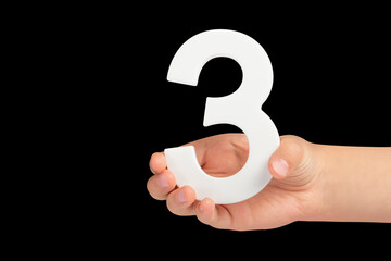 Aufkleber - number three in hand isolated on black background. Number three in a child's hand on a black background. To be inserted into a project or design.