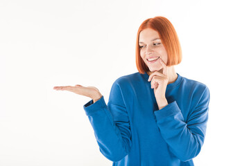 Wall Mural - The girl holds a copy space for advertising in the palm of her hand and thinks on a white background.