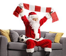 Excited Santa Claus Sitting On A Sofa With A Football And Cheering With A Scarf