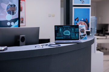 Wall Mural - Computerized tomography showing brain activity. Personal laptop screen showing scans with diagnosis of sick person on empty hospital reception front desk with no health professionals.