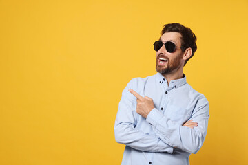 Portrait of excited bearded man with stylish sunglasses on orange background. Space for text