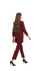 Wall Mural - Young woman in burgundy suit walking on white background