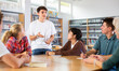 © JackF - Group of fifteen-year-old schoolchildren are discussing something and making notes in copybooks, preparing for classes in the school library