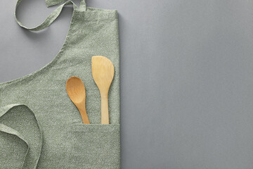 Poster - Clean apron with wooden kitchen tools on light grey background, top view. Space for text