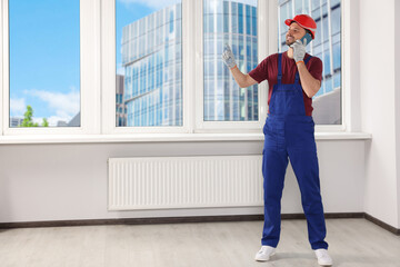 Poster - Professional repairman in uniform talking on phone indoors, space for text