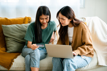 Poster - Two asian young woman happy smiling and using computer laptop on couch in living room at home