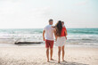 © vera - Happy family. Father and mother with son on hands on beach in summer vacation. Run, play and get fun on sand near sea together. Sunny day and good weather. white and red clothes.