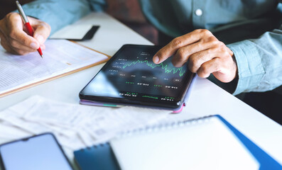 Asian businessman using tablet computer to analysis investment plan and check report in paperwork