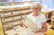© Robert Kneschke - Ältere Bäckerin mit Erfahrung zeigt stolz ein Laib Brot