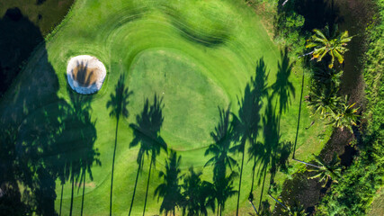 Aerial view of green golf course and putting green, Aerial view of green grass and coconut palm trees on gree golf field, fairway, sand bunker  and putting green.