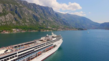 Wall Mural - Aerial video. A big cruize ship is moving through the Boka Kotor Bay. Summer in Montenegro. Slowmotion shot