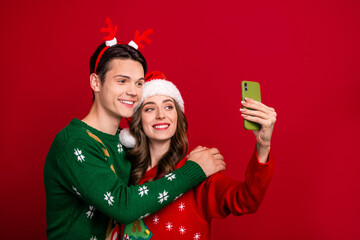 Sticker - Portrait of two peaceful cheerful people embrace hold telephone make selfie isolated on red color background