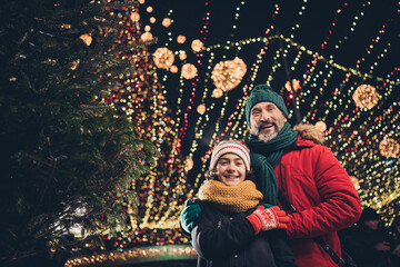 Wall Mural - Photo of funny cheerful young husband school boy enjoying xmas atmosphere cuddling outdoors city fair