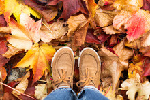 Person In Boots Standing On Dry Autumn Leaves