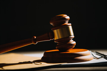 Justice and law concept.Male judge in a courtroom with the gavel, working with, computer and docking keyboard, eyeglasses, on table in morning light