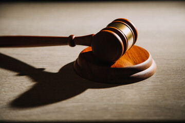 Justice and law concept.Male judge in a courtroom with the gavel, working with, computer and docking keyboard, eyeglasses, on table in morning light