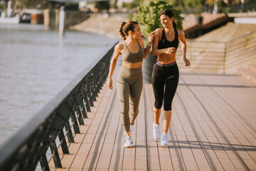 Wall Mural - Young woman taking running exercise by the river promenade