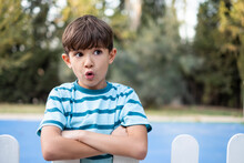Little Boy Looking At Camera Behind The Wooden Fences With Surprise Expression