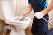 © Ruslan Ivantsov - plumber unclogging blocked toilet with hydro jetting at home bathroom