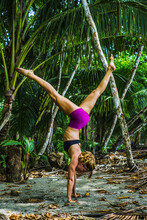 Side View Of Fit Woman Performing Handstand In Forest