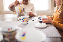 Close Up Of Young Girl And Great Grandmother Playing With Tea Set