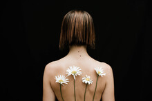 Naked Woman With Chamomiles On Her Back Against Black Background