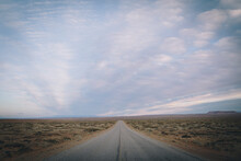 The Open Road Extends Into The Desert With A Sunset Sky.
