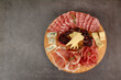 Italian appetizers or antipasto set with gourmet food on black background, top view. Mixed delicatessen of cheese and meat snacks. Charcuterie board. Format of the banner.	