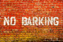 NO BARKING Sign Painted On The Wall Of A Bright Red Brick Building.