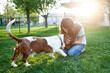 © Cavan Images - Tween girl kissing Basset Hound dog on head in the green grass at home