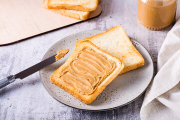 Wall Mural - Bread toast with peanut butter on a plate and a jar of butter on the table