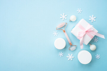 Poster - Natural winter cosmetic with holiday decorations and present box on blue background. Winter scincare concept. Flat lay image.