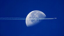 Plane Jet Trails Over The Moon Blue Sky