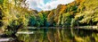 Beautiful view of a lake with swimming ducks, surrounded by colorful autumn trees