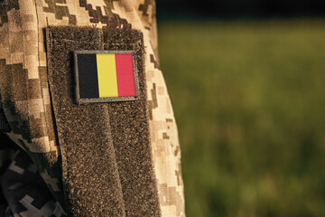 Wall Mural - Close up millitary woman or man shoulder arm sleeve with Belgium flag patch. Belgium troops army, soldier camouflage uniform. Armed Forces, empty copy space for text
