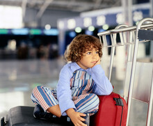 Kid Sitting On Top Of Suitcase Waiting