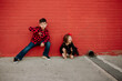 © Erin Brant/Stocksy - Portrait of brother and sister in front of red wall