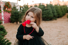 Little Girl Hold Red Bow Headband While Eating Candy Cane
