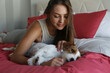 © Evrymmnt - Portrait of young beautiful woman and her adorable jack russell terrier puppy on the bed in the morning. Loving girl with her broken coated dog feeling cozy at home. Background, close up, copy space.