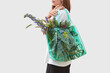 © Yaroslav Danylchenko/Stocksy - Woman holding recycled bag filled with flowers.