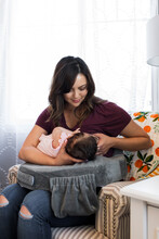 New Mother Nurses Infant Using A Nursing Pillow