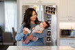 © McKinsey Jordan/Stocksy - Mother Prepares A Bottle In The Kitchen While Holding Child