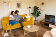 © BONNINSTUDIO/Stocksy - Couple lounging in living room