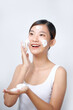 © Marc Tran/Stocksy - Smiling young woman washing foam face by natural foamy gel.